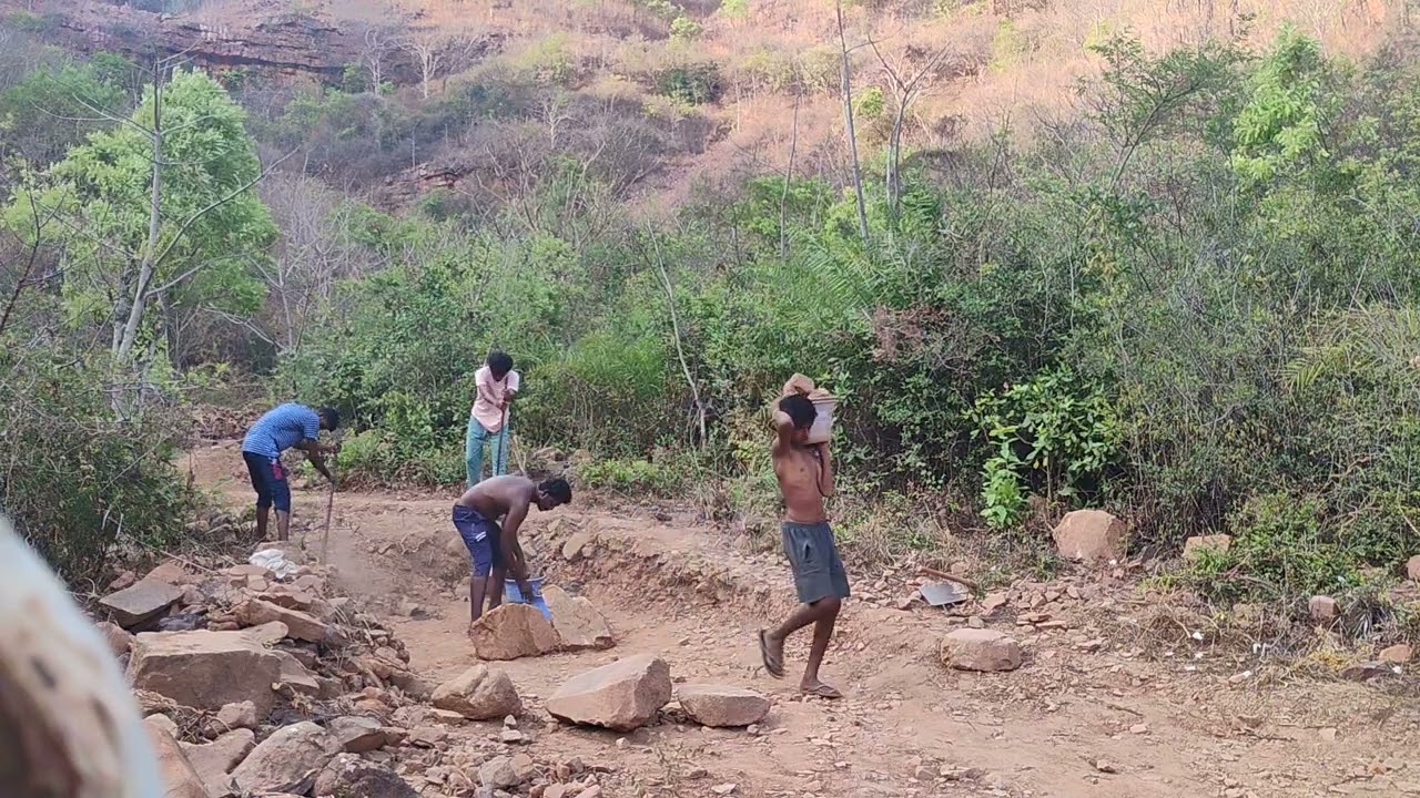 People digging soil and carrying big rock into the washout, before the bridge was built.